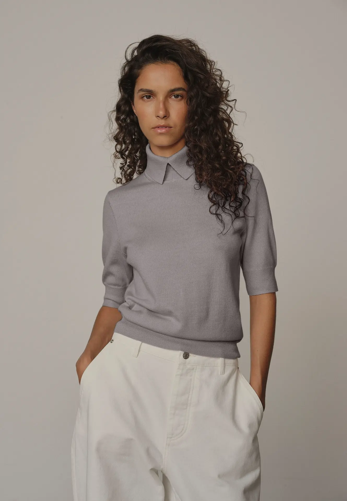 Nouvelle collection de pull Herskind SP26 Jeune Femme portant un jeans blanc et pull gris avec col