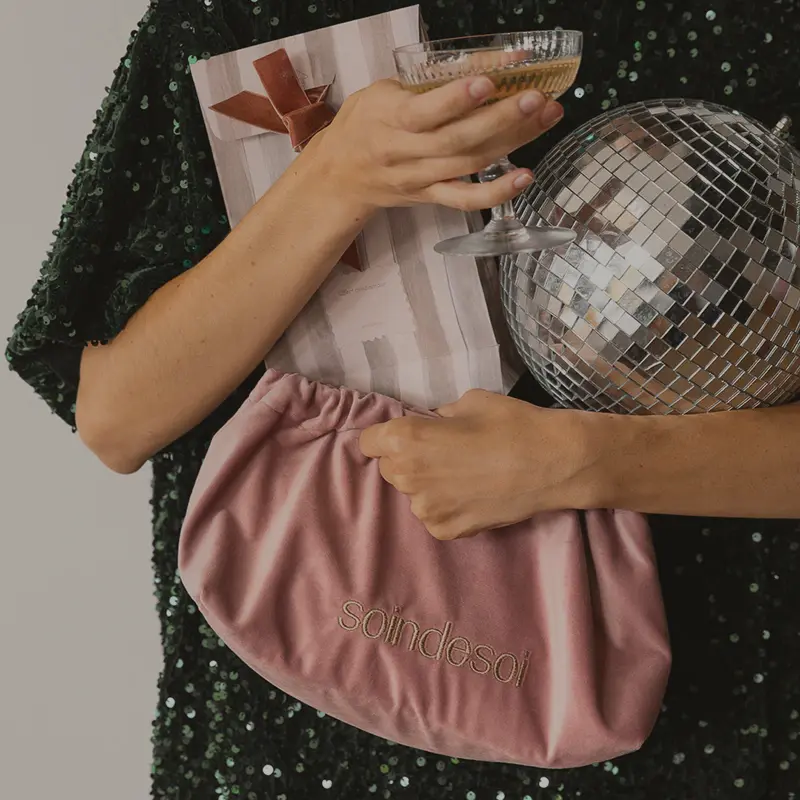 Femme portant dess cadeaux Soin de Soi et une coupe de champagne